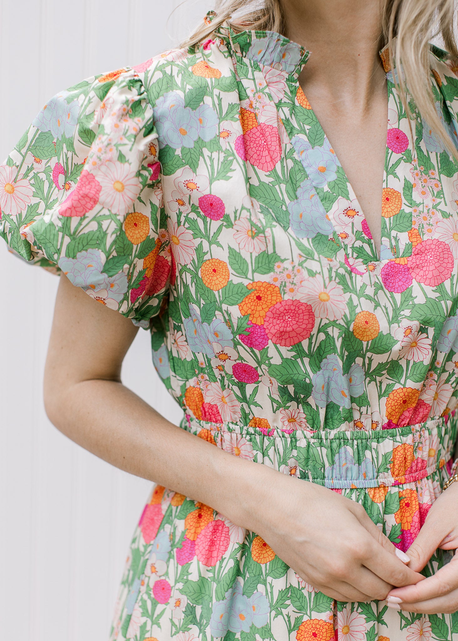 Close up of short puff sleeve, v-neck, ruffle neck and smocked bodice on bright floral maxi. 