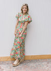 Model wearing a bright floral maxi with short puff sleeves, elastic waist and a ruffle neck. 