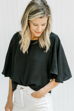 Model wearing a black polyester crop top with flutter short sleeves and a round neckline. 