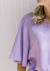 Close up of flutter short sleeves on a lavender top that is slightly cropped. 