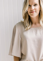 Close up of flutter short sleeves on a taupe polyester crop top. 