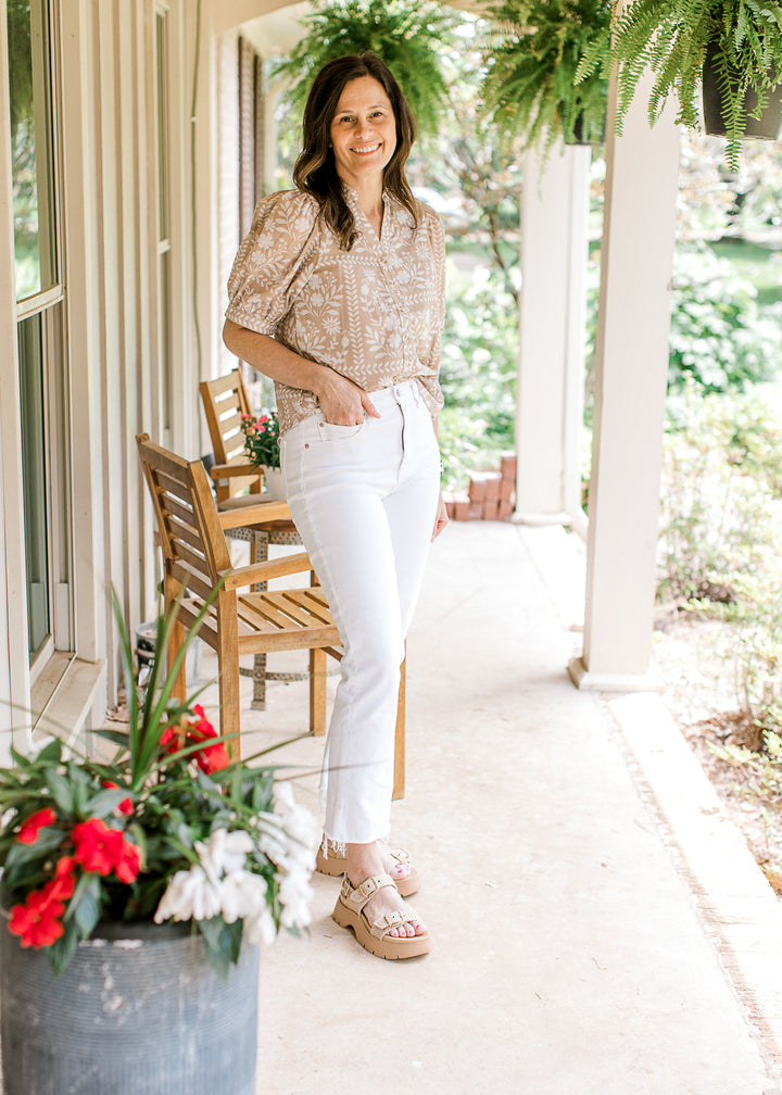 Model wearing white jeans, wedges and a wheat top with white floral, short sleeves and v-neck.