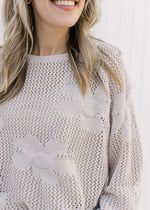 Close up of stitched flowers on an oatmeal color knit sweater with bubble long sleeves.