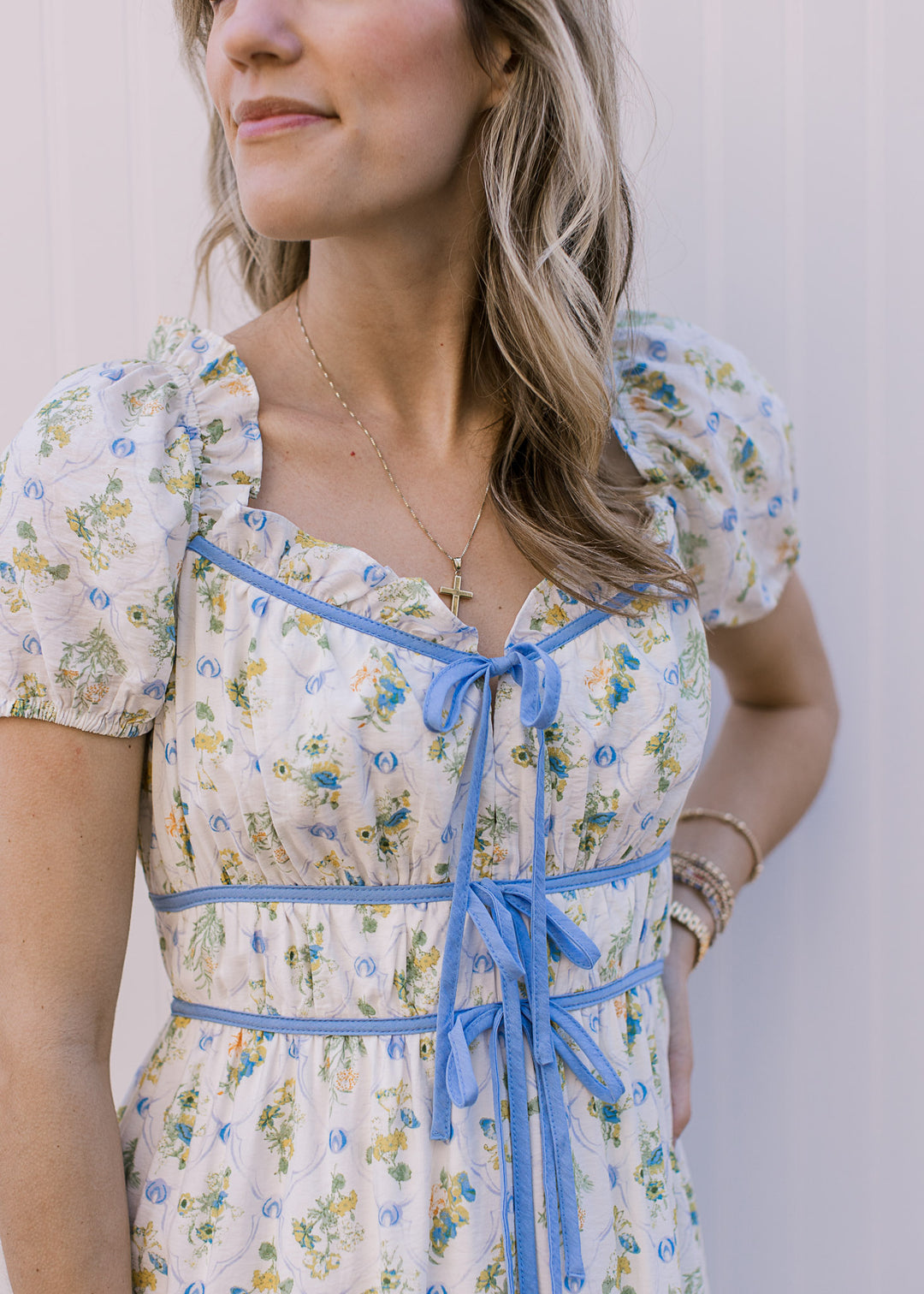 Close up of pale blue tie at v-neck and double ties at waist of an off white midi with floral. 