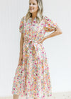Model wearing a cream v-neck dress with a mixed colored floral pattern and short puff sleeves. 