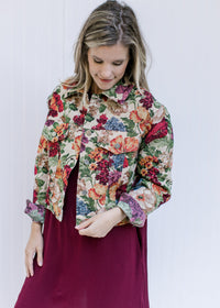 Model wearing a red dress with a floral tapestry jacket with a button closure and a crop fit.