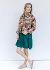 Model wearing a green dress with a floral tapestry jacket a button closure and a crop fit.