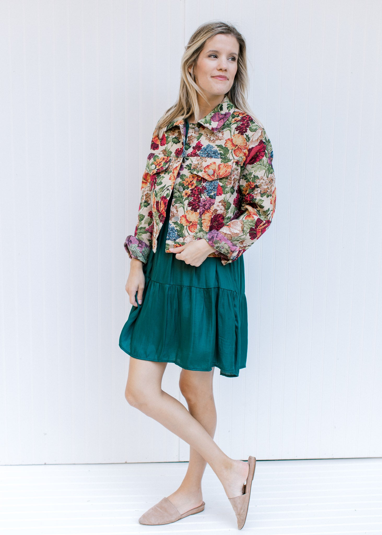 Model wearing a green dress with a floral tapestry jacket a button closure and a crop fit.