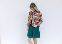 Model wearing a long sleeve floral tapestry jacket with a button closure and a crop fit.
