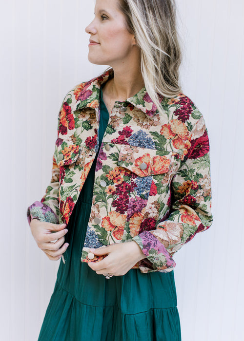 Model wearing a floral tapestry jacket with long sleeves, a button closure and a crop fit. 