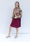 Model wearing mules and a red dress with a long sleeve floral tapestry jacket with a crop fit.
