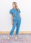 Model wearing mules and a medium washed denim jumpsuit with wide legs and short sleeves. 