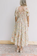 Back view of model wearing a yellow and pink floral dress with a smocked back and square neck.