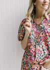 Close up view of Model wearing a bright floral v-neck top with bubble short sleeves.