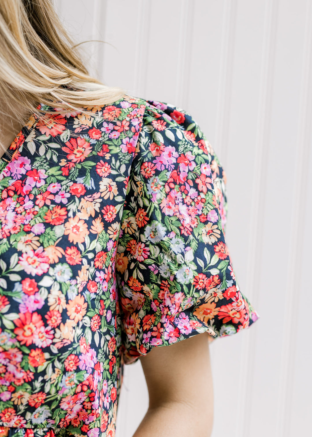 Close up view of bubble short sleeve on a bright floral top with a black background.