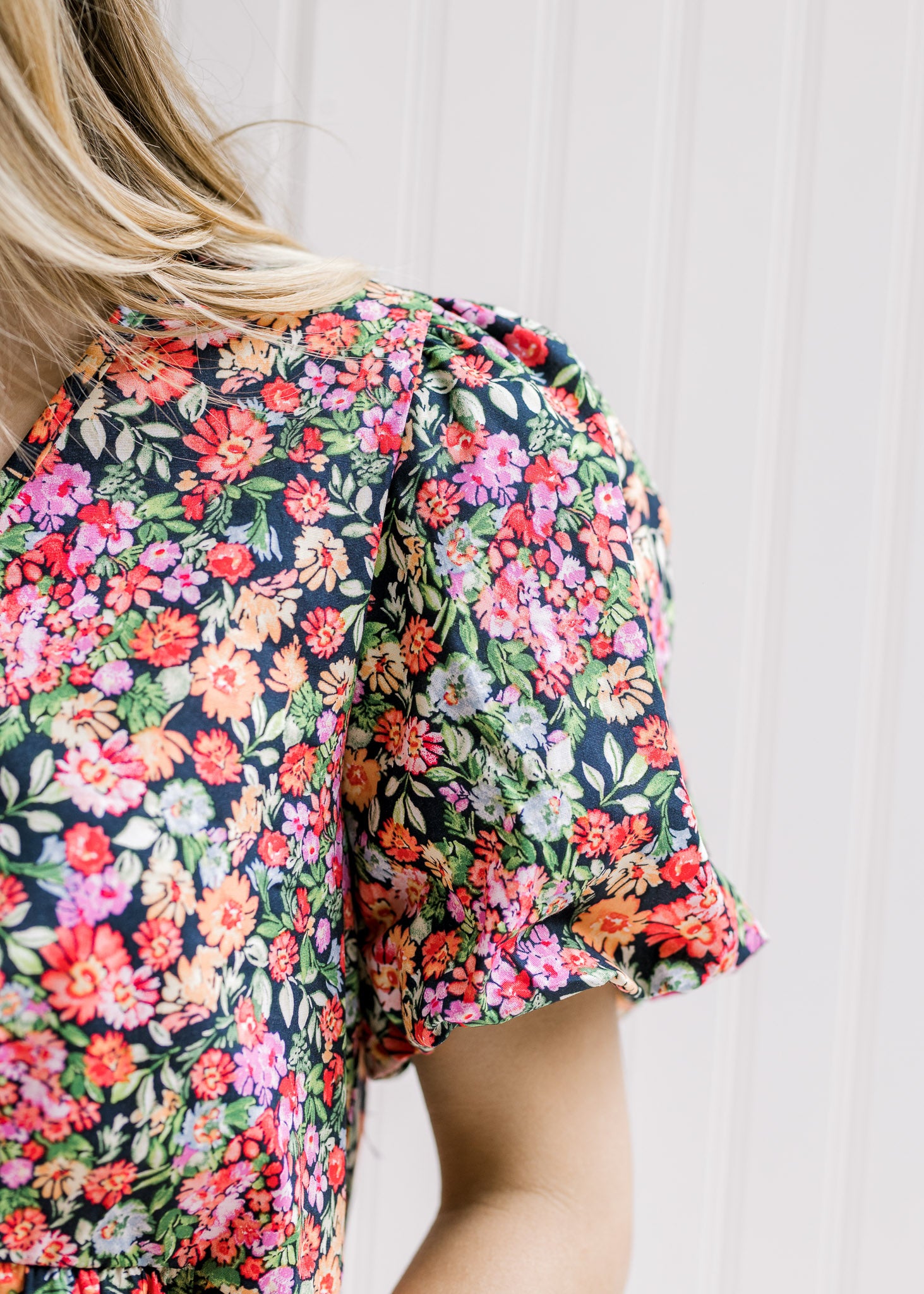 Close up view of bubble short sleeve on a bright floral top with a black background.