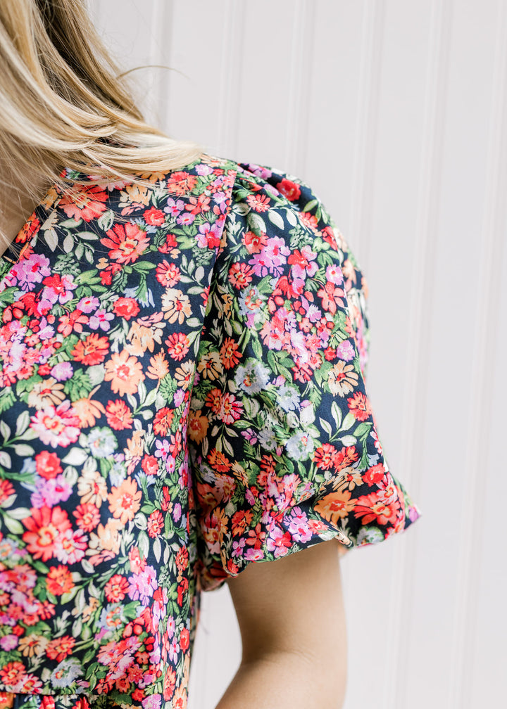 Close up view of bubble short sleeve on a bright floral top with a black background.