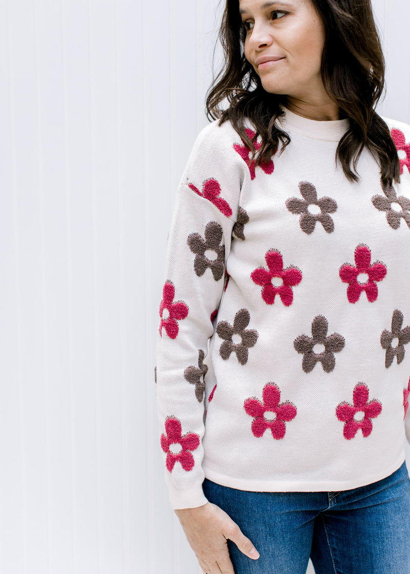 Model wearing an ivory sweater with maroon and brown floral pattern, long sleeves and a round neck.