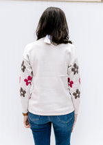 Back view of a solid ivory back on an ivory sweater with brown and maroon flowers and long sleeves.
