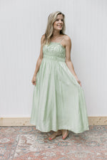 Model wearing a pale green midi with a smocked bust, adjustable straps with a pleated detail.
