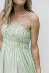 Close up of smocked bust and adjustable spaghetti straps on a pale green midi. 