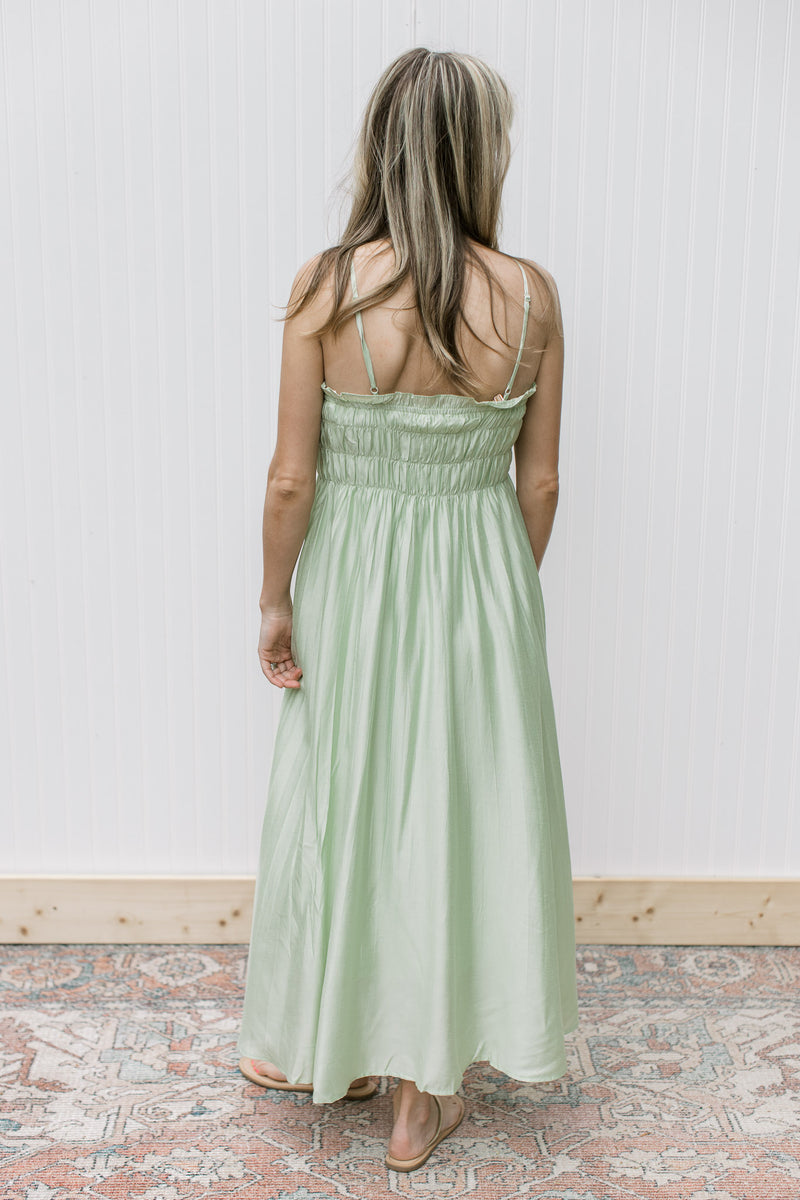 Back view of Model wearing a pale green midi with a smocked bust and adjustable straps.