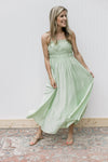 Model in a pale green dress with a smocked bust, adjustable straps with a flowy fit. 