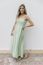Model wearing a fully lined pale green dress with a smocked bust and adjustable straps. 