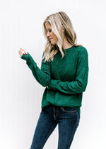 Model wearing jeans and a forest green long sleeve sweater with a textured material and a crew neck.
