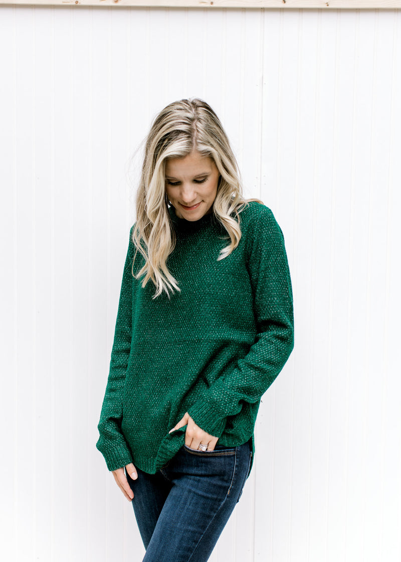 Model wearing a forest green long sleeve sweater with a textured material and a crew neckline. 