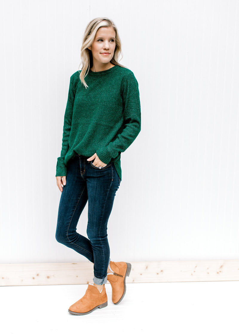 Model wearing jeans, booties and a forest green sweater with a textured material and long sleeves. 