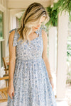 Model wearing a white tiered midi with light blue floral, tie spaghetti straps and a v-neck. 
