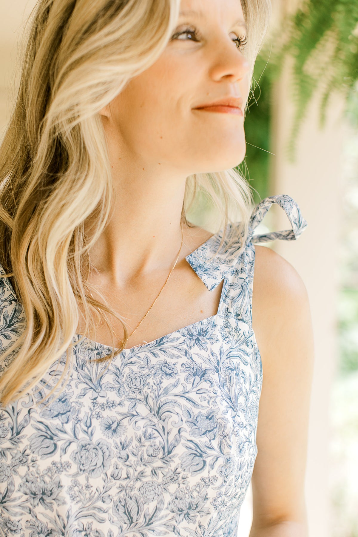 Close up on v-neck and tie spaghetti stripes on a white midi with tiers and blue floral. 