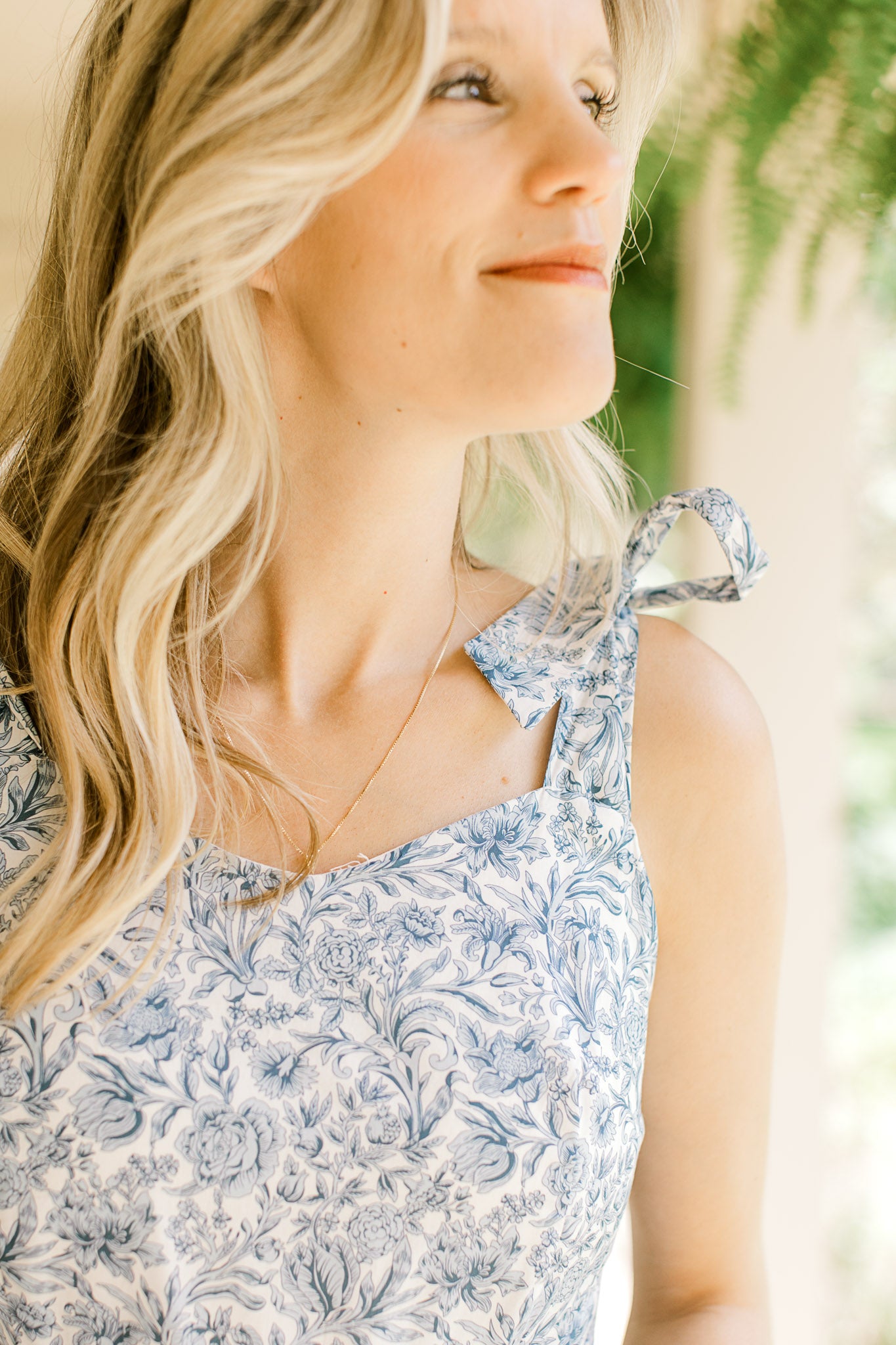 Close up on v-neck and tie spaghetti stripes on a white midi with tiers and blue floral. 