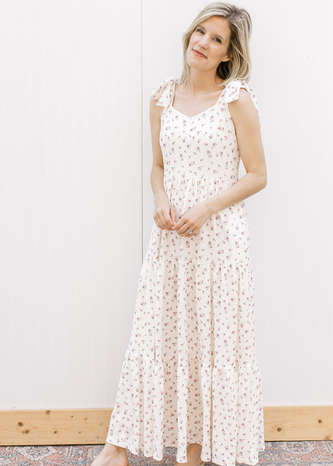 Model wearing a cream midi with pale purple floral, v-neck, adjustable tie straps and tiered skirt.