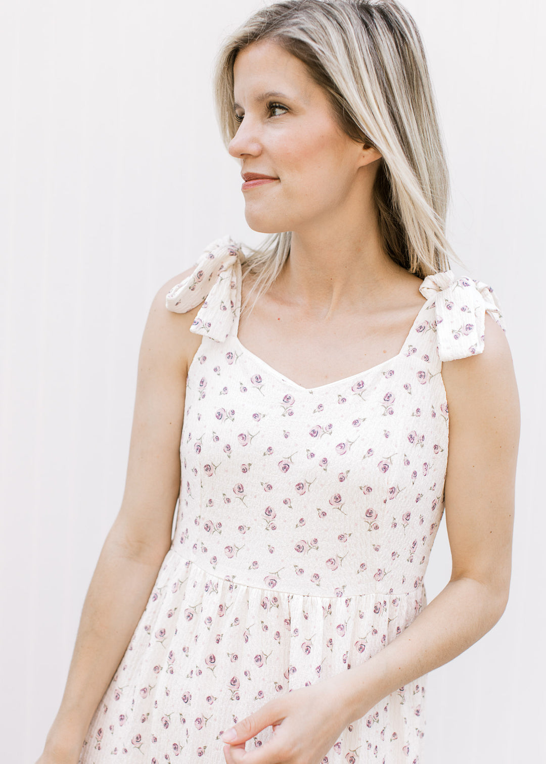 Close up of v-neck and tie straps on a cream midi with pale purple flowers and hidden zipper. 