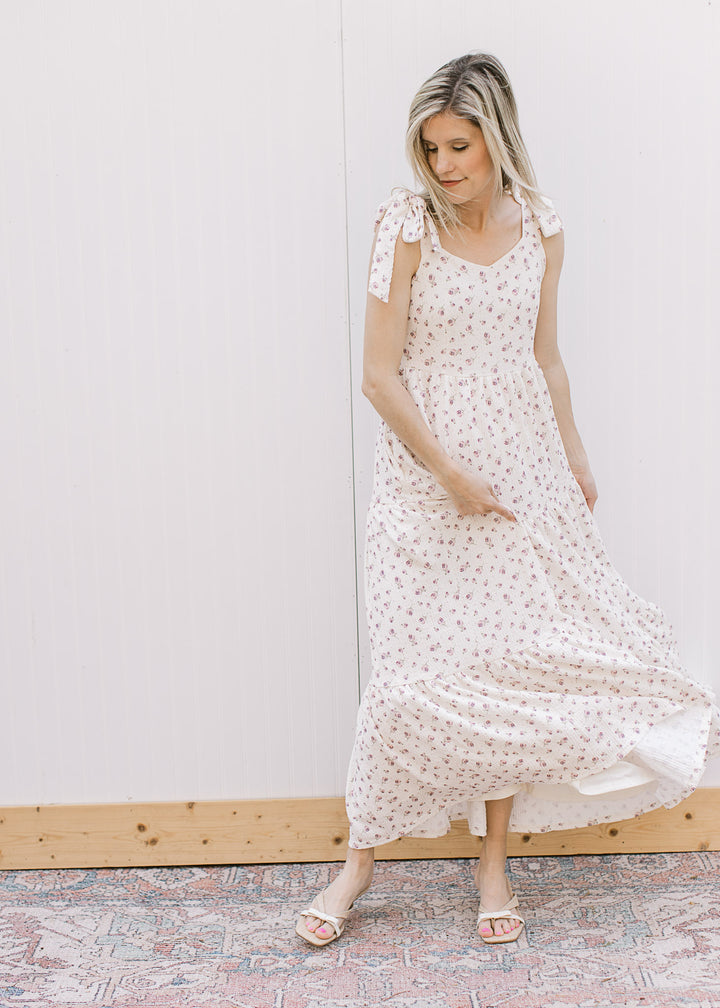 Model wearing heels and a cream midi with pale purple floral, v-neck, tie straps and tiered skirt.
