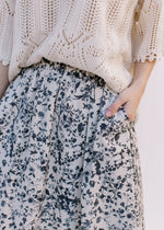 Close up of black floral pattern and pockets on a cream midi skirt with an elastic wasitband