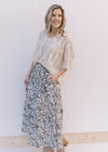 Model wearing a cream midi skirt with black floral pattern, pockets and an elastic waistband.