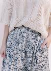 Model wearing a cream sweater with a cream skirt with black floral pattern and an elastic waist.
