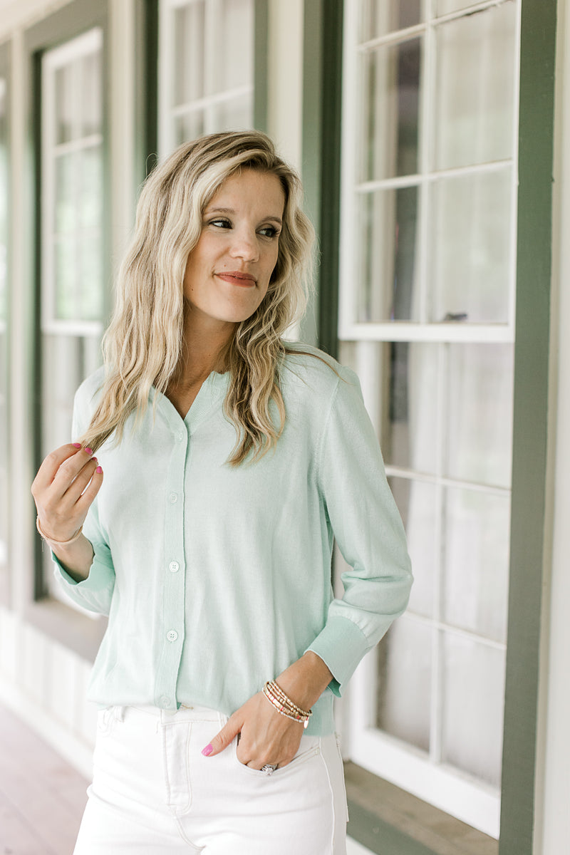 Model wearing a button up mint green cardigan with 3/4 sleeves.