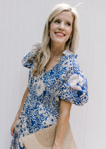 Close up of bubble short sleeves and ruffle on a blue maxi with cream floral pattern. 