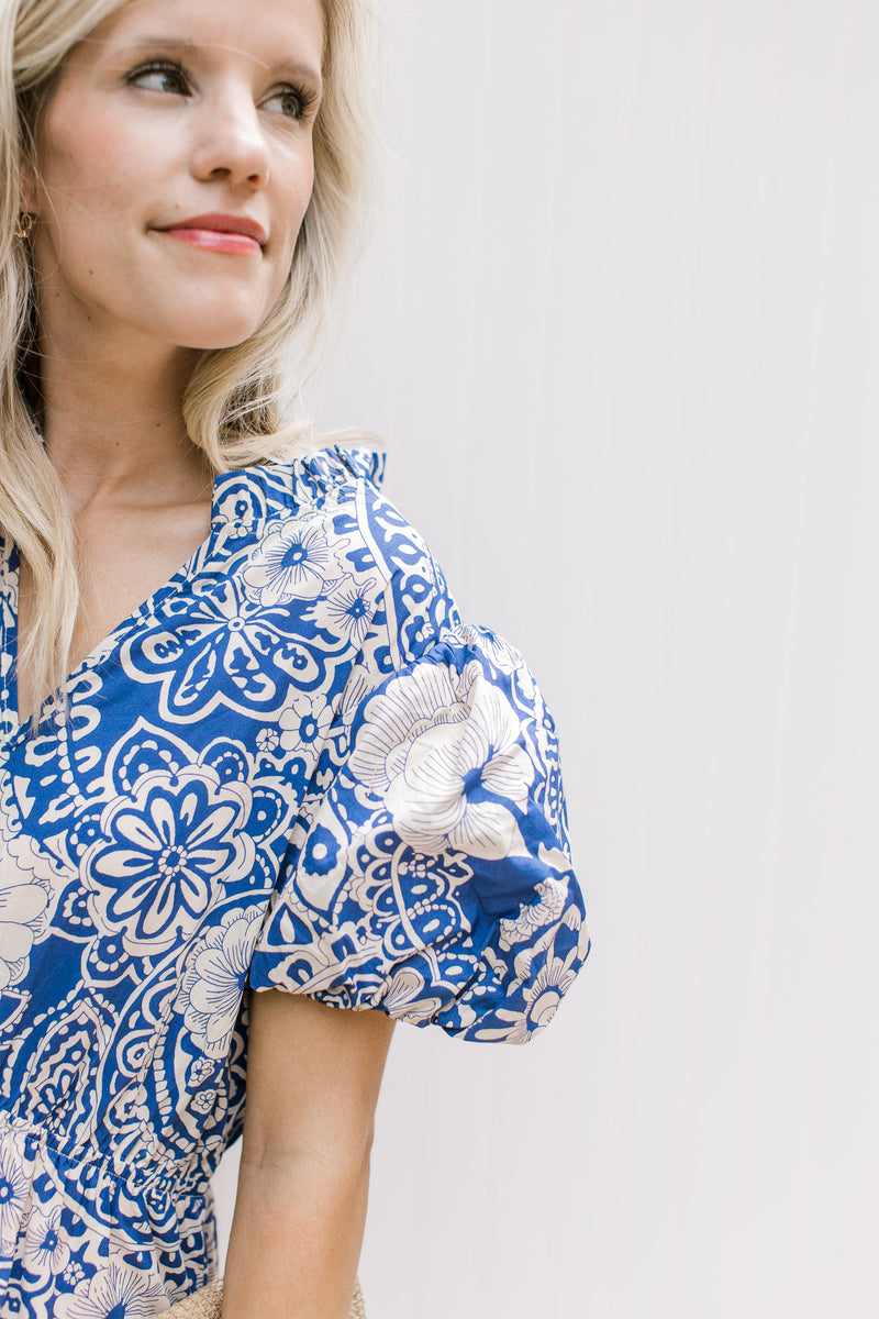 Close up of bubble short sleeve and v-neck on a blue maxi with cream floral pattern. 