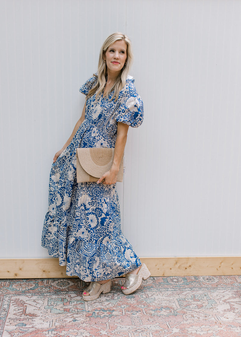 Model wearing wedges with a blue maxi dress with cream floral, ruffle neck and short puff sleeves.