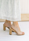 Model wearing heels with a clear vamp and a cork heel. 