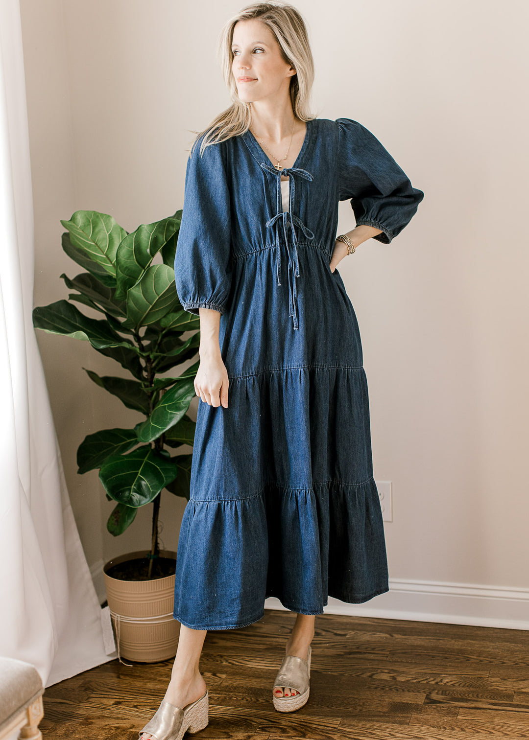 Model wearing wedges and a dark denim midi with a 3/4 sleeves and an open neck with a front ties. 