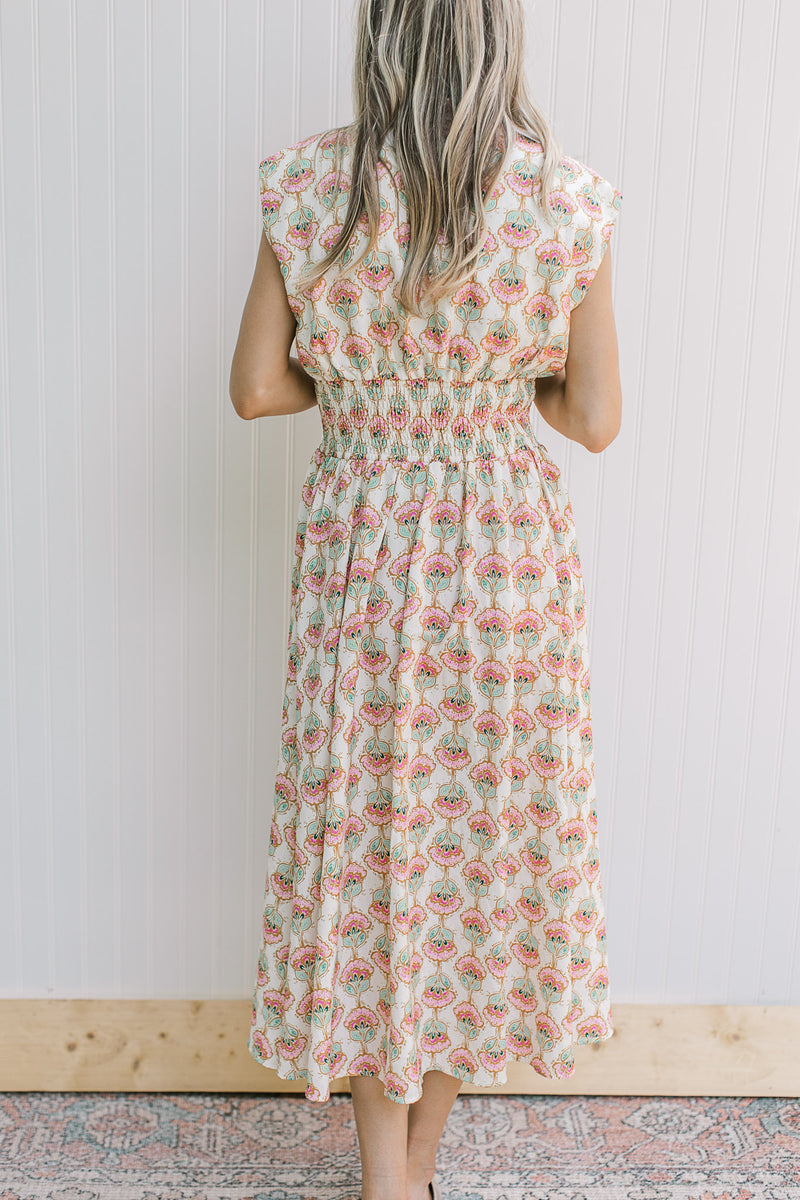 Back view of Model wearing a cream midi with pink peonies, smocked waist and cap sleeves.