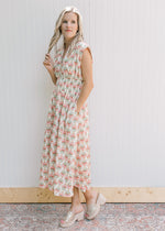 Model wearing a cream midi with pink peonies, cap sleeves and a full front zip.