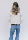 Back view of Model wearing an ivory open front coat with a crop cut, pockets and long sleeves. 