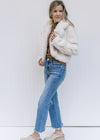 Model wearing jeans, mules and a camel top with an ivory open front coat with long sleeves. 